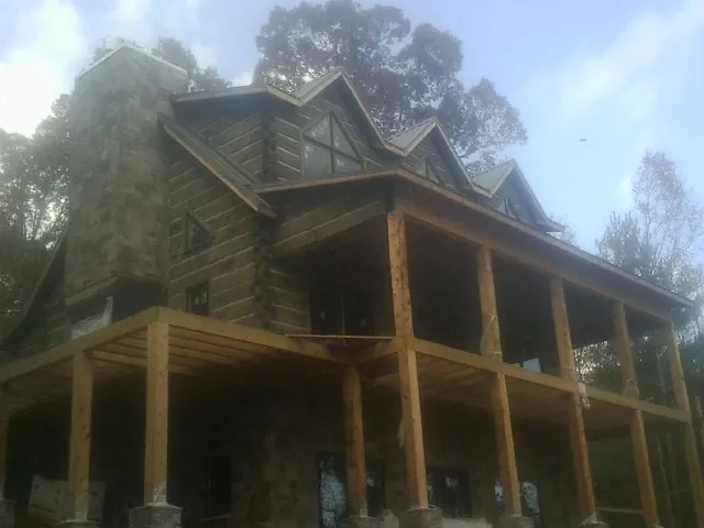 Stone chimney and dormers on a large log home with a timber porch in Dayton